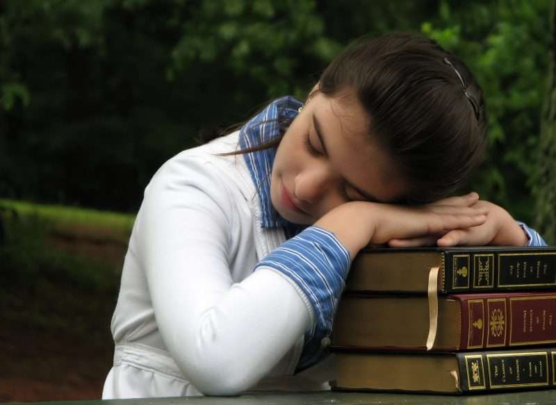 Student sleeping over a stack of books