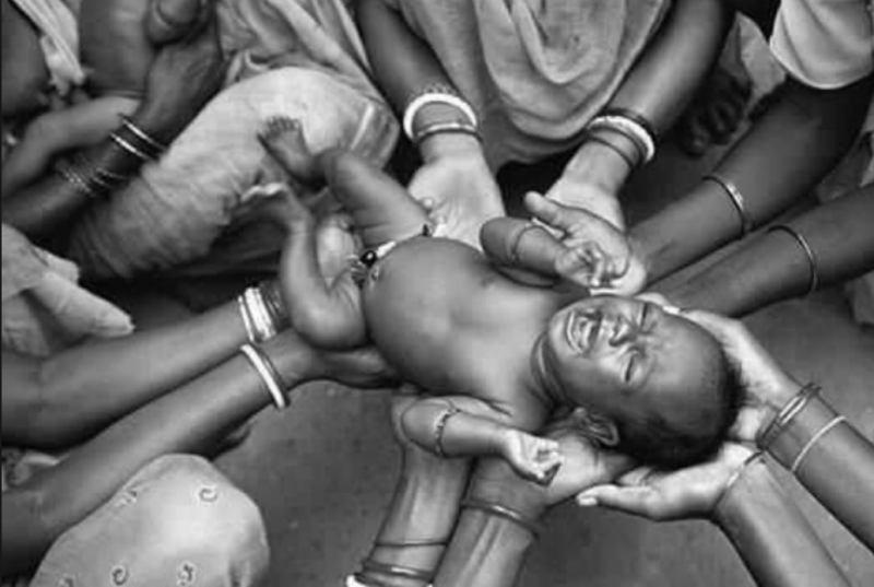 Baby being held by a community