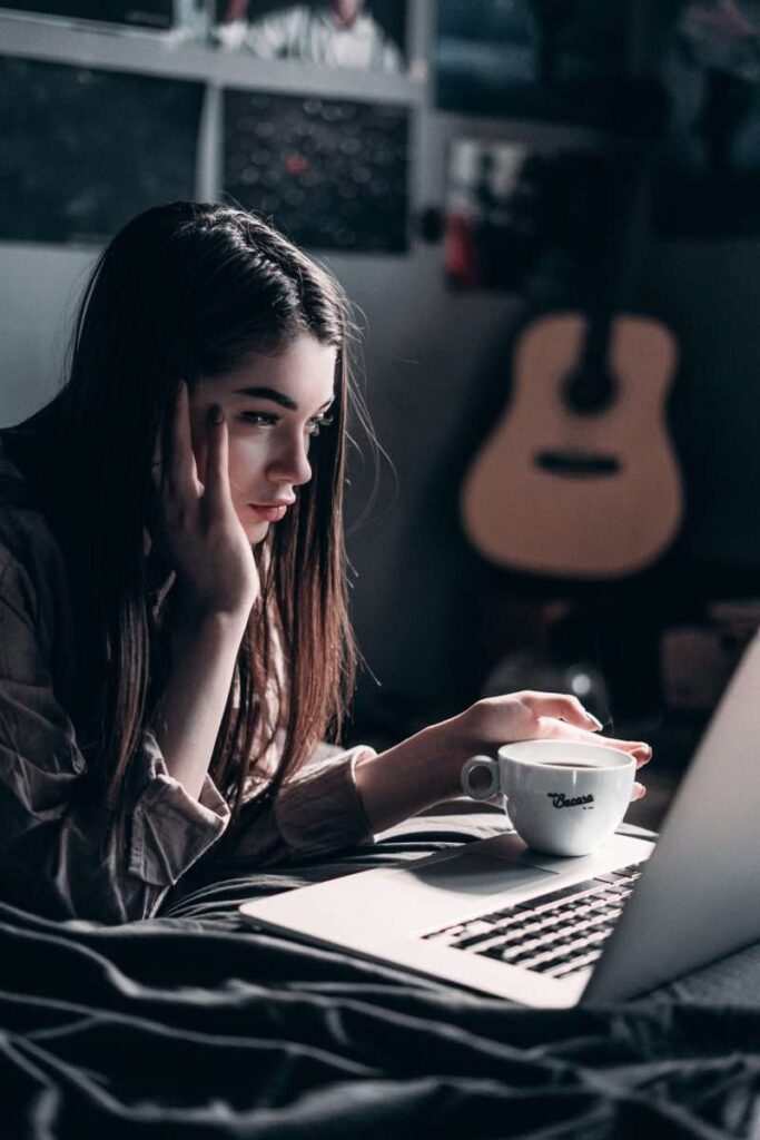 Young woman on bed looking at laptop