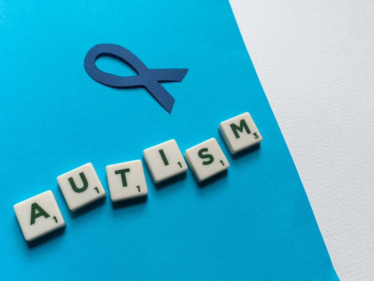 Blue Autism Awareness Ribbon and Scrabble Tiles on Blue Paper