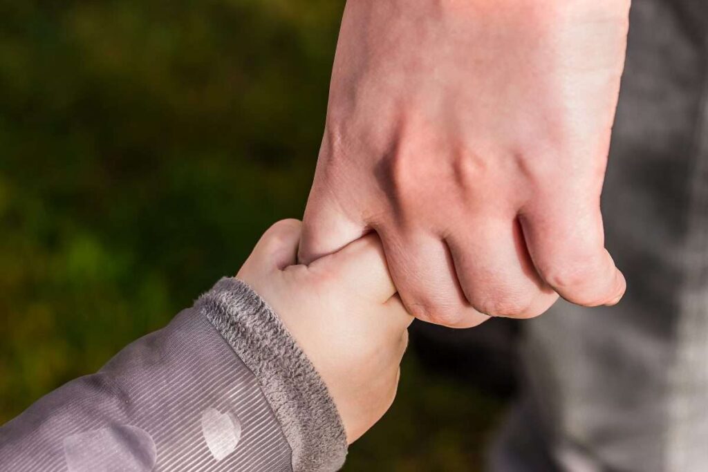 Adult holding child's hand - teaching life skills