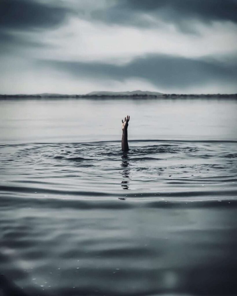 hand of person drowning sticking out of the water