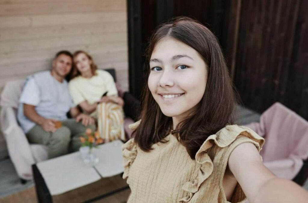 Tween girl selfie with parents in background