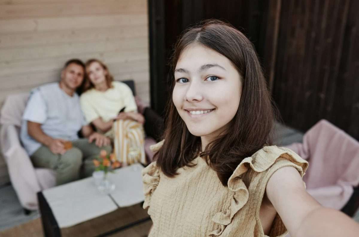 Tween girl selfie with parents in background