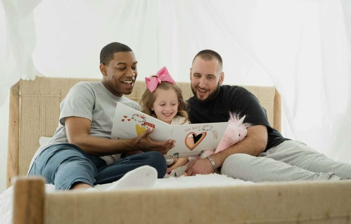 Two fathers reading with their daughter