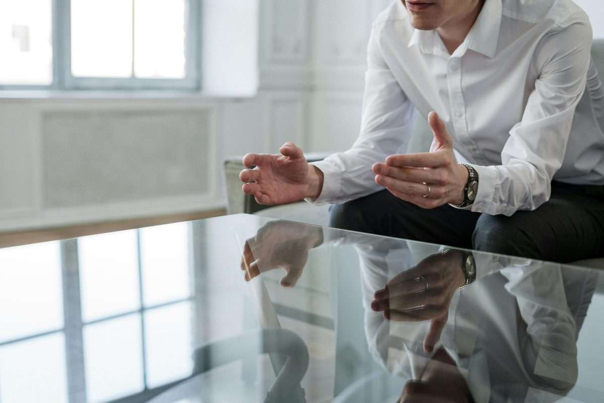 male with hands above a glass table