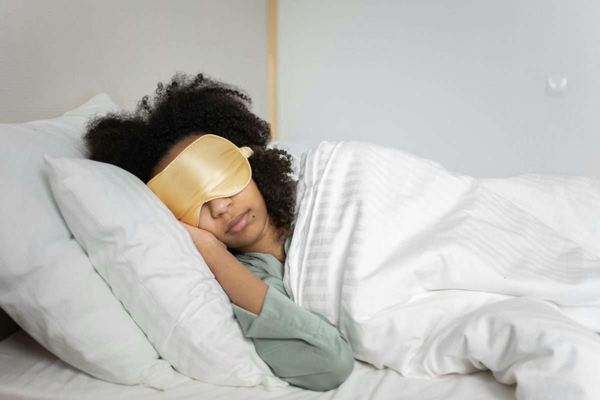 teen girl with sleep mask in bed