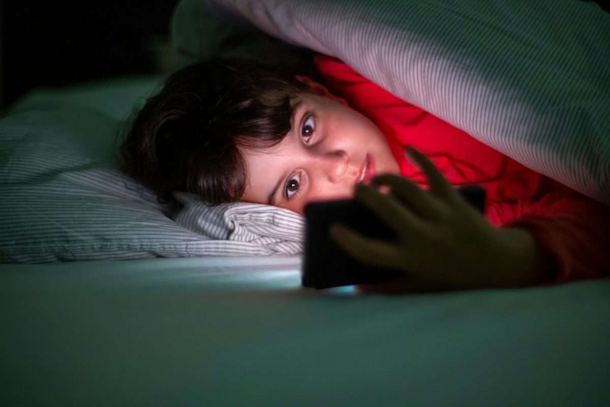 boy looking at device in bed