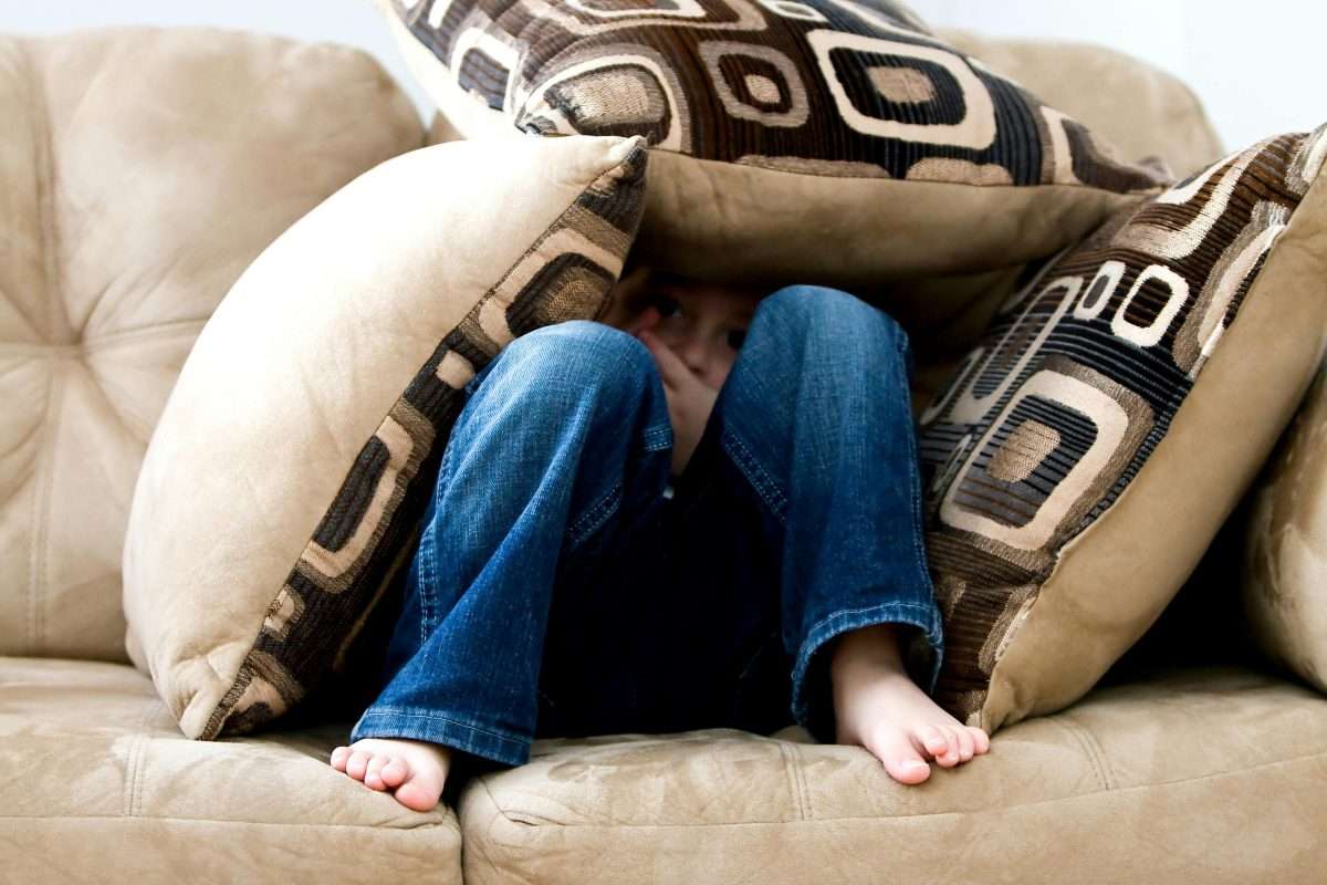 young child hiding within pillows