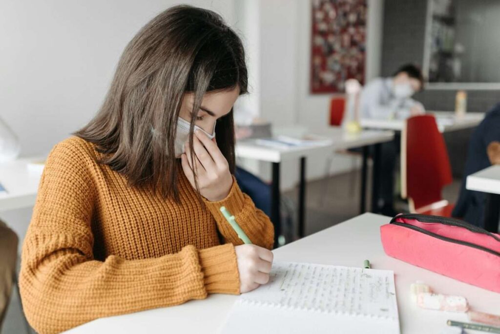 tween with mask working on desk in classroom