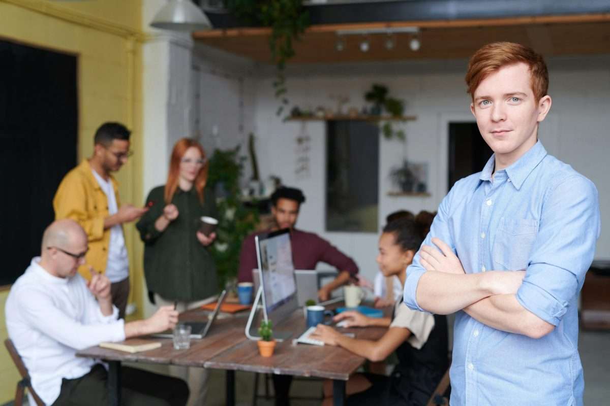 Man Standing Beside People Sitting Beside Table With Laptops 