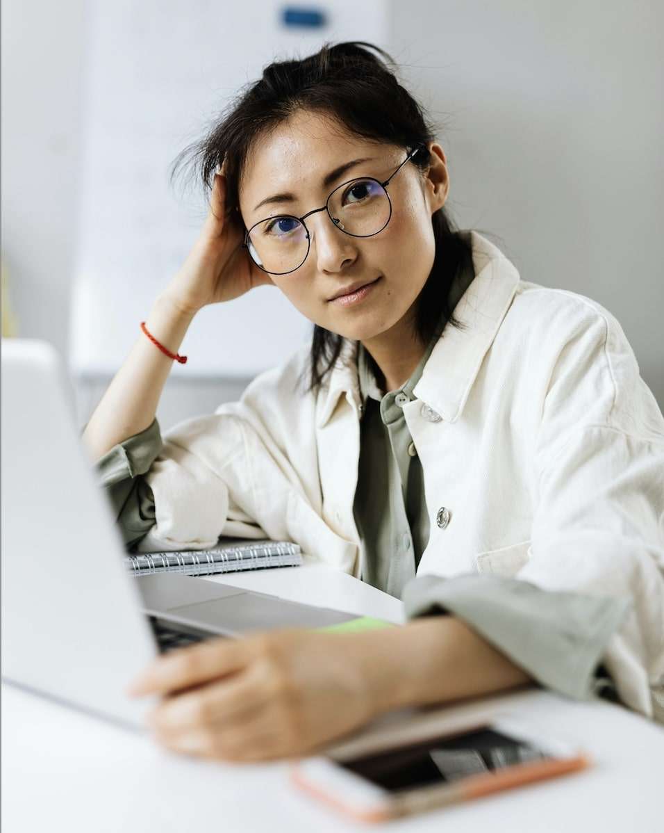 Asian female in front of laptop looking to camera