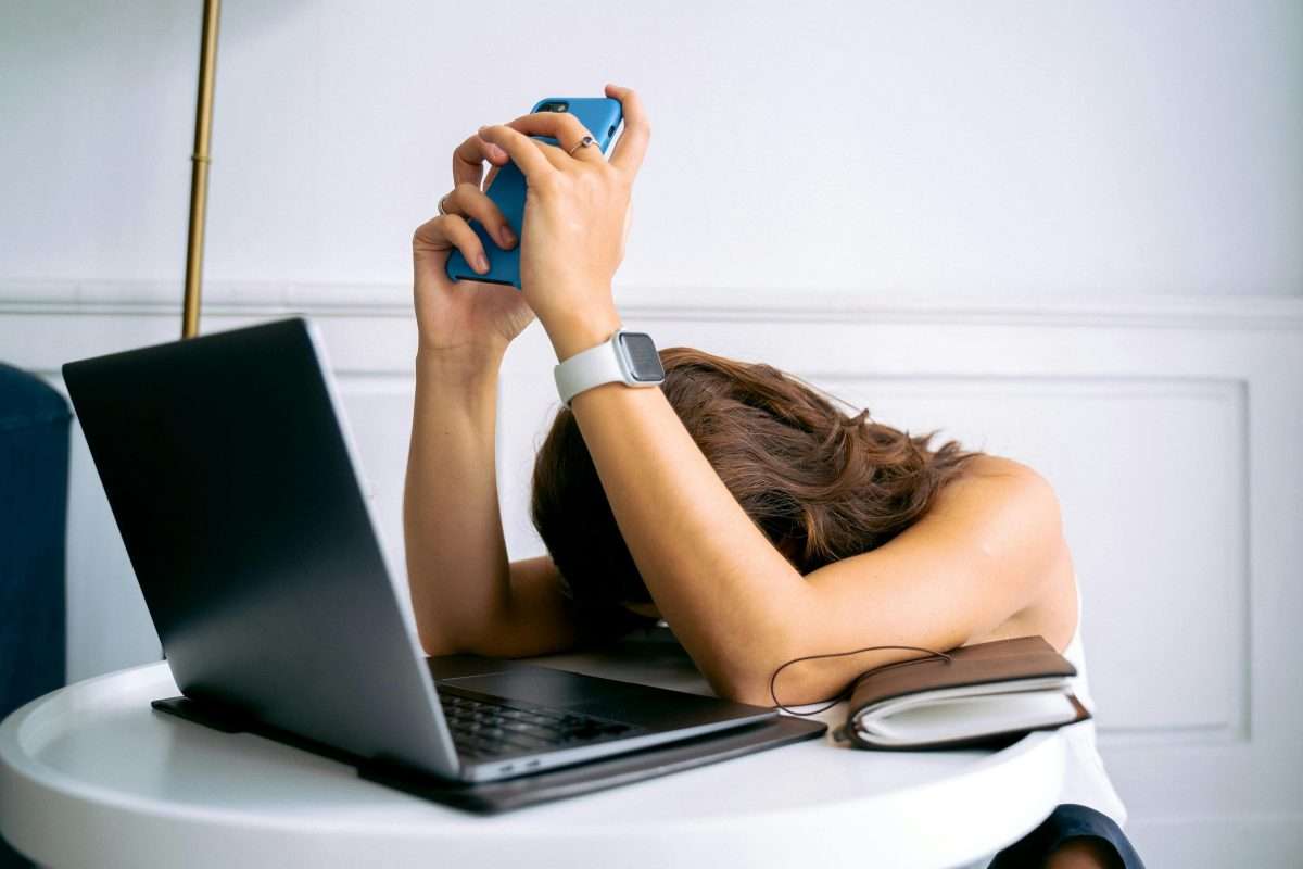 Young woman hanging her head over laptop