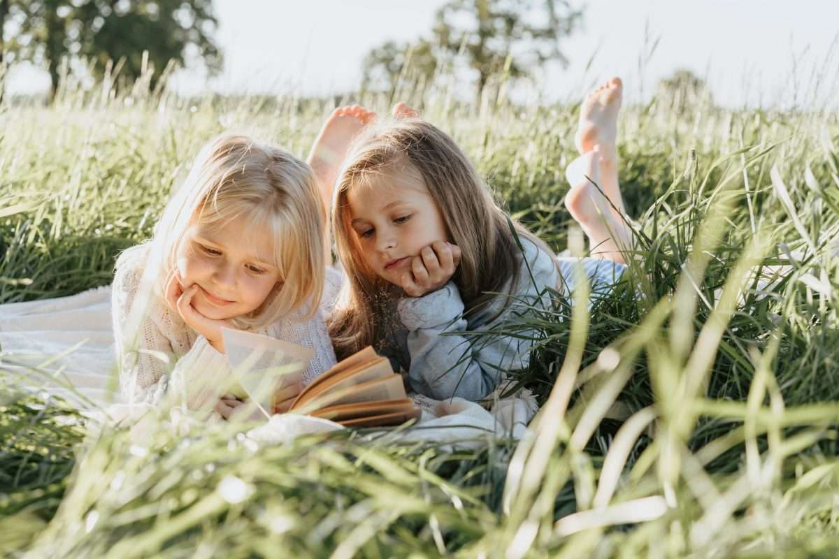 two young girls reading in the grass